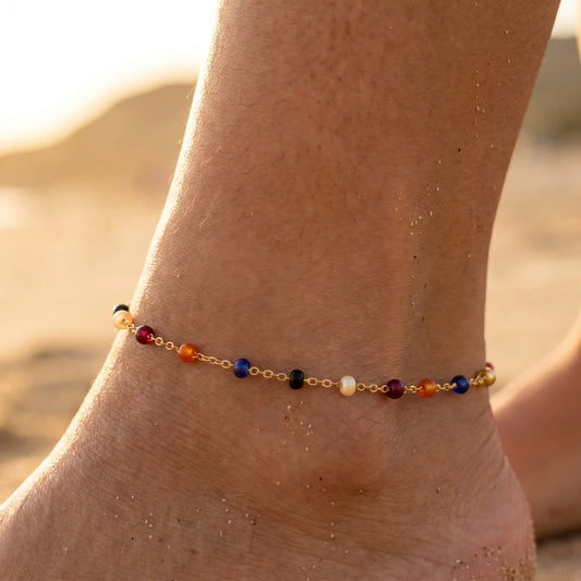Multicolor bead anklet on tanned ankle at golden hour beach close-up