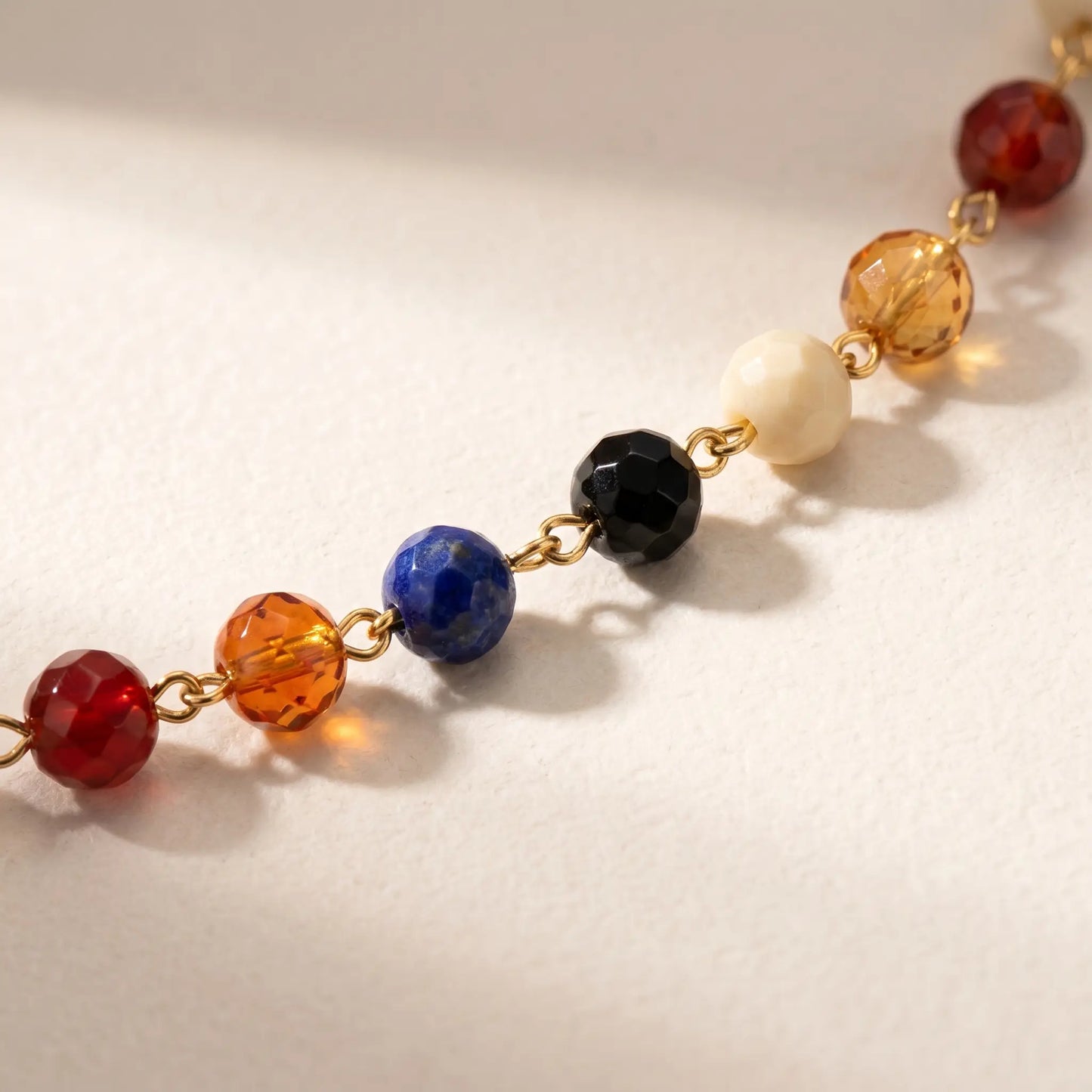Macro detail of multicolor glass beads on fine gold cable chain anklet