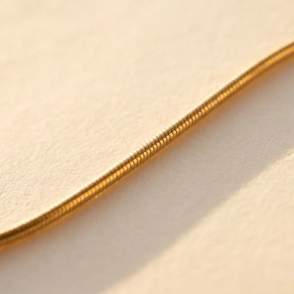 Gold snake chain macro detail showing smooth round tubular cross-section