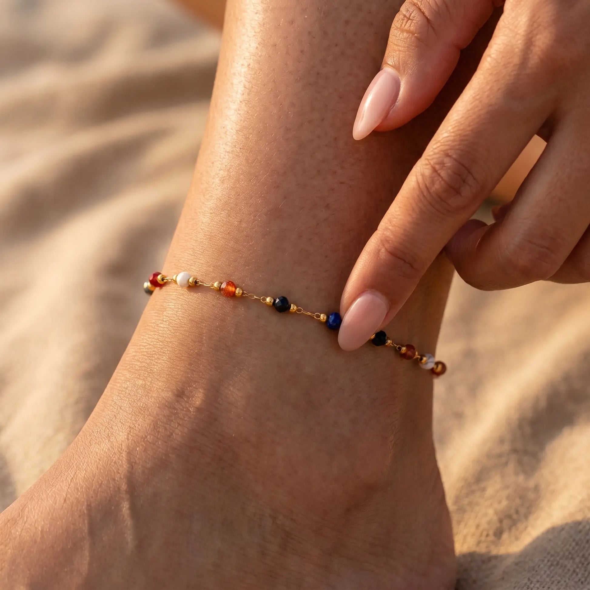 Hand fingertips touching multicolor beaded anklet on tanned ankle
