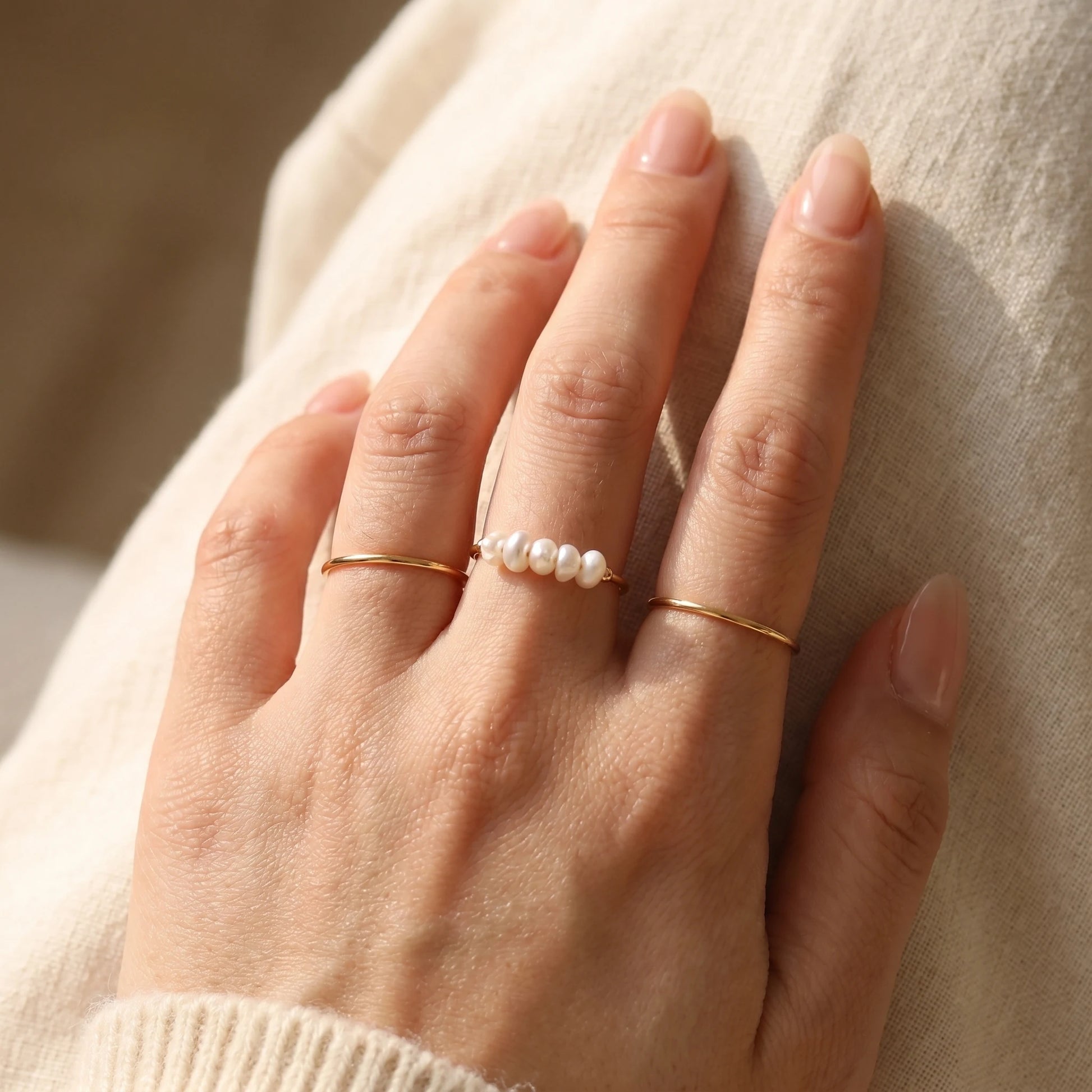 Gold Dainty Pearl Bar Ring stacked with plain bands on hand
