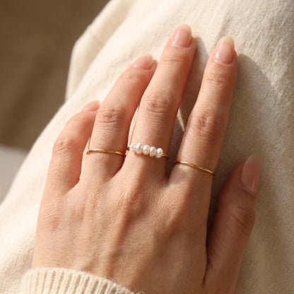 Gold Dainty Pearl Bar Ring stacked with plain bands on hand