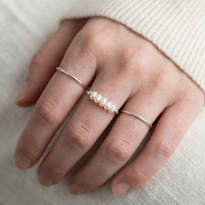 Silver Dainty Pearl Bar Ring stacked with plain silver bands on hand