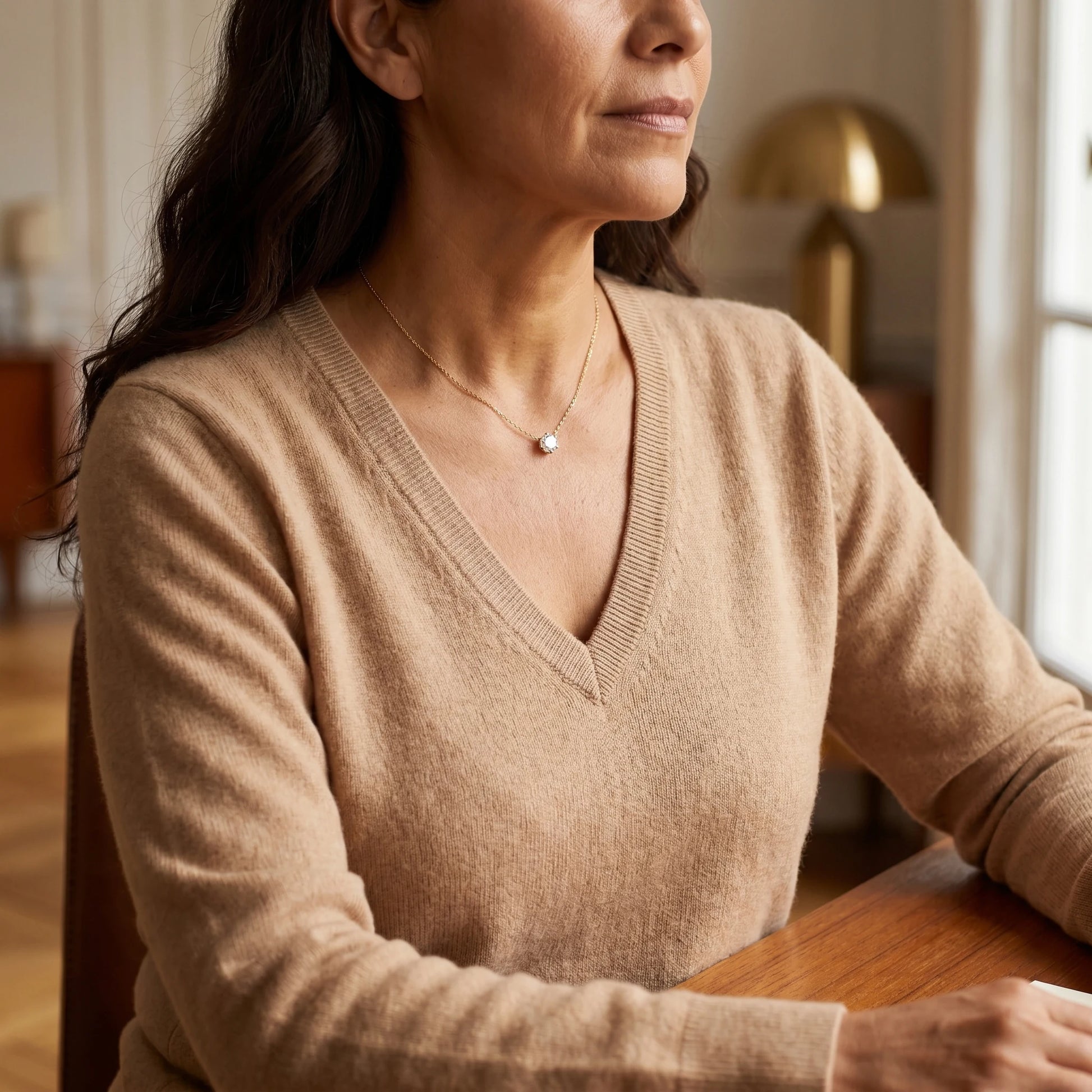 Floating Solitaire Necklace Gold - 3/4 portrait on woman in camel V-neck, Parisian interior