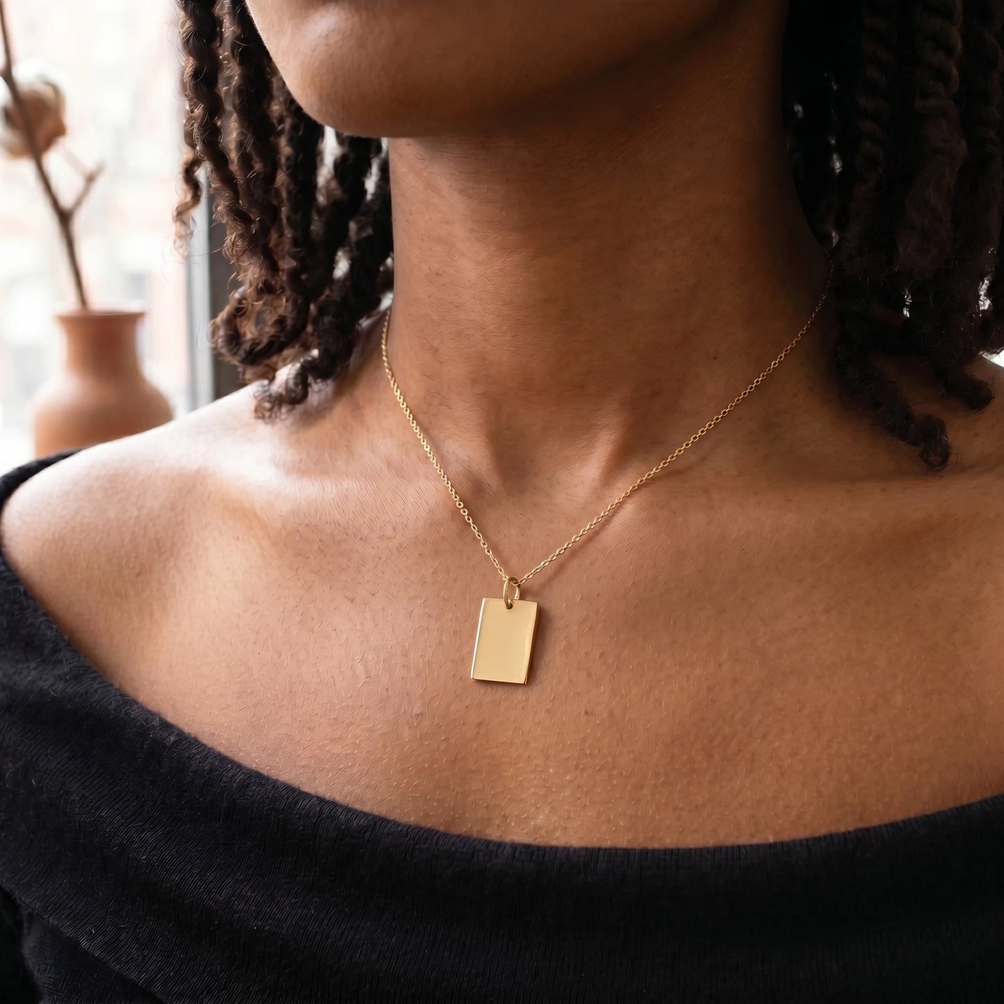 Gold rectangle pendant necklace worn close-up dark skin straight vertical orientation sharp corners