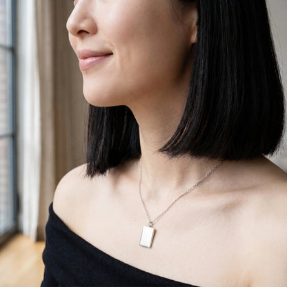 Silver rectangle pendant profile editorial subtle smile off-shoulder black