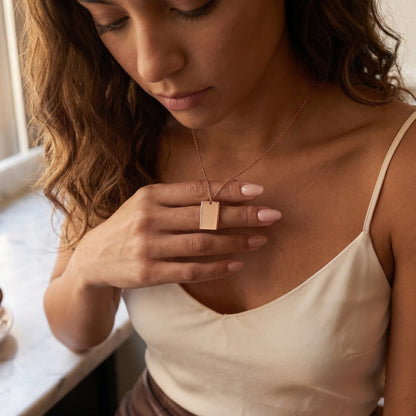 Rose gold rectangle pendant intimate hand-to-pendant moment Latina silk cami
