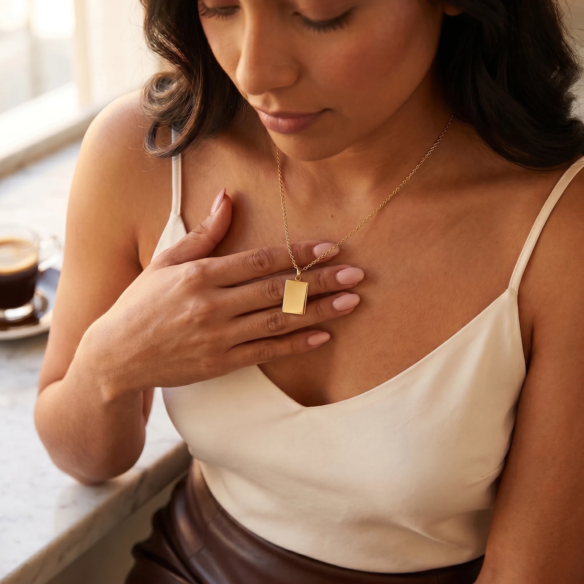 Gold rectangle pendant intimate hand-to-pendant moment Parisian cafe