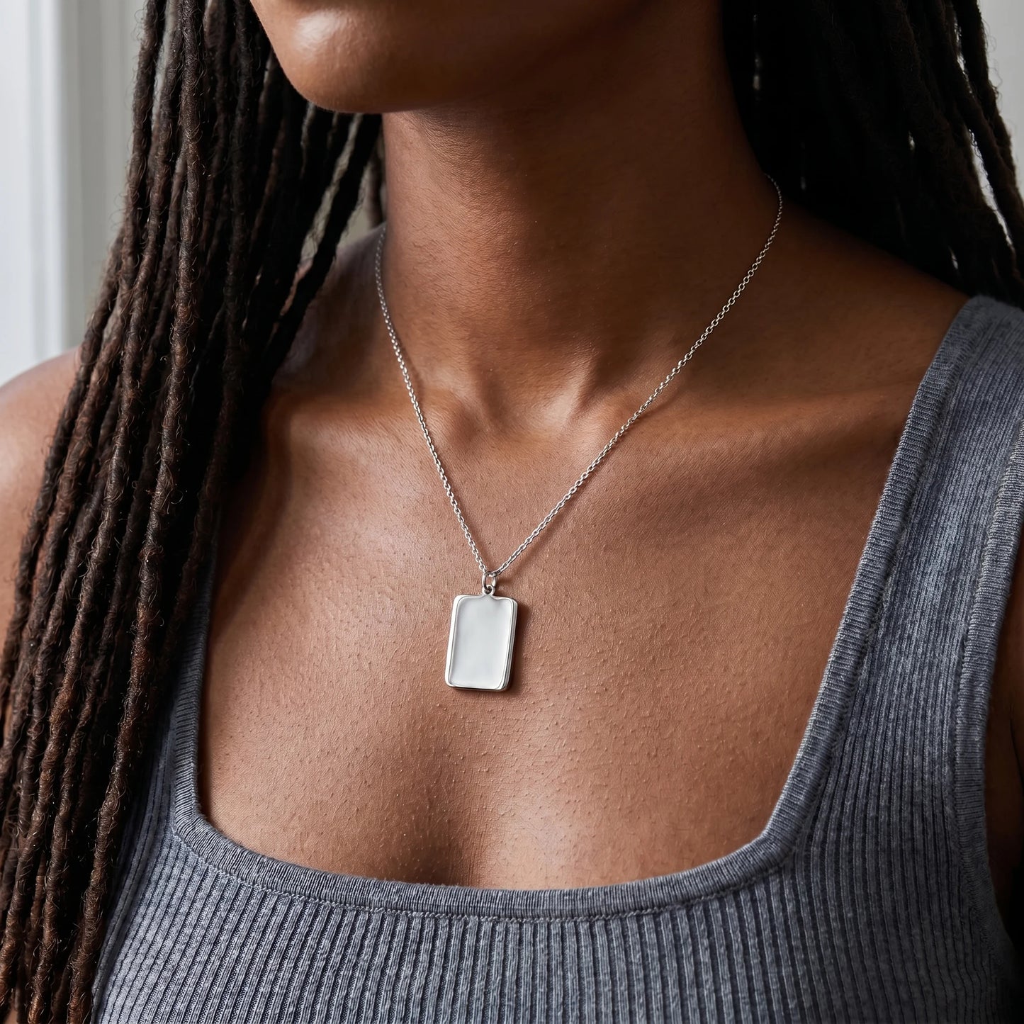Silver rectangle pendant necklace worn close-up at clavicle sharp corners