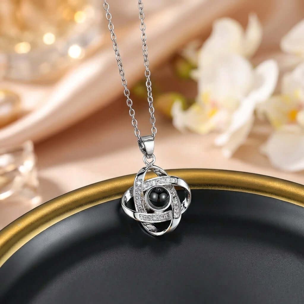 Photo Projection Necklace by AUREATE featuring a unique pendant design in silver and black on a decorative plate.