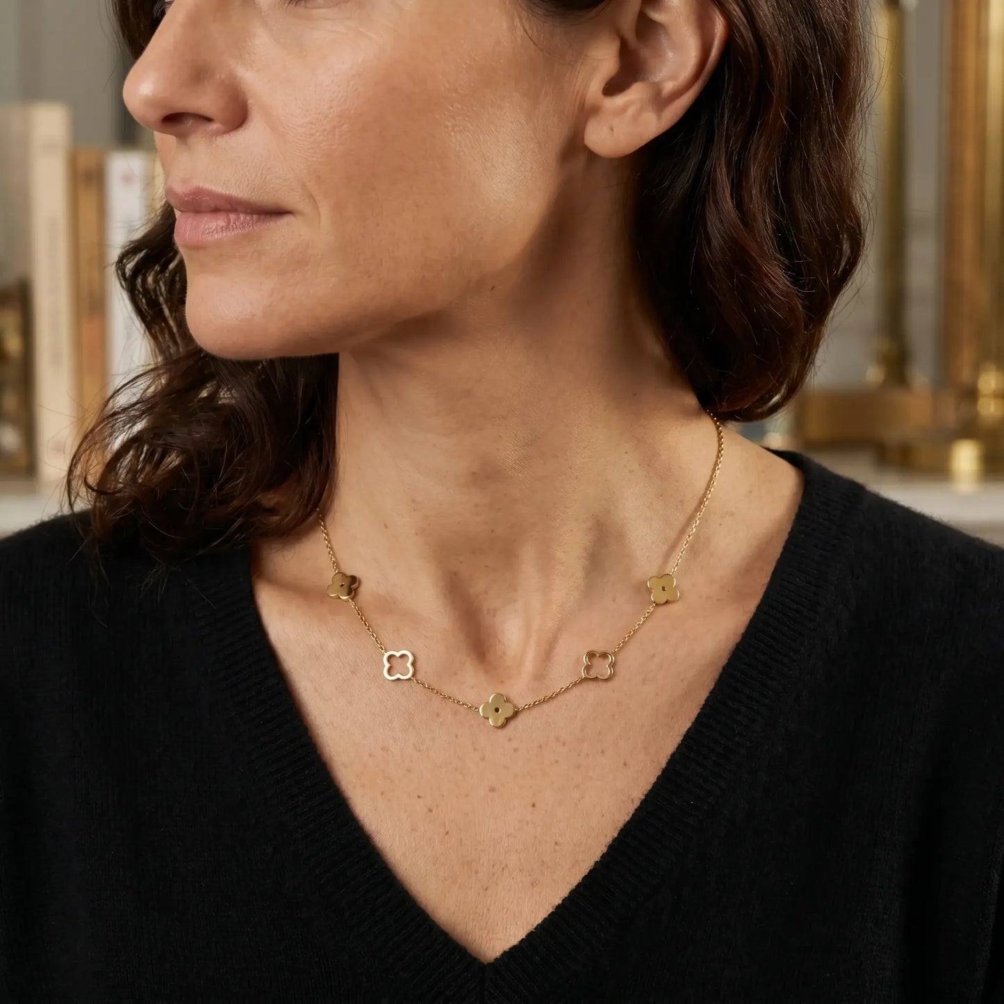 Four leaf clover necklace gold styled on woman black cashmere V-neck