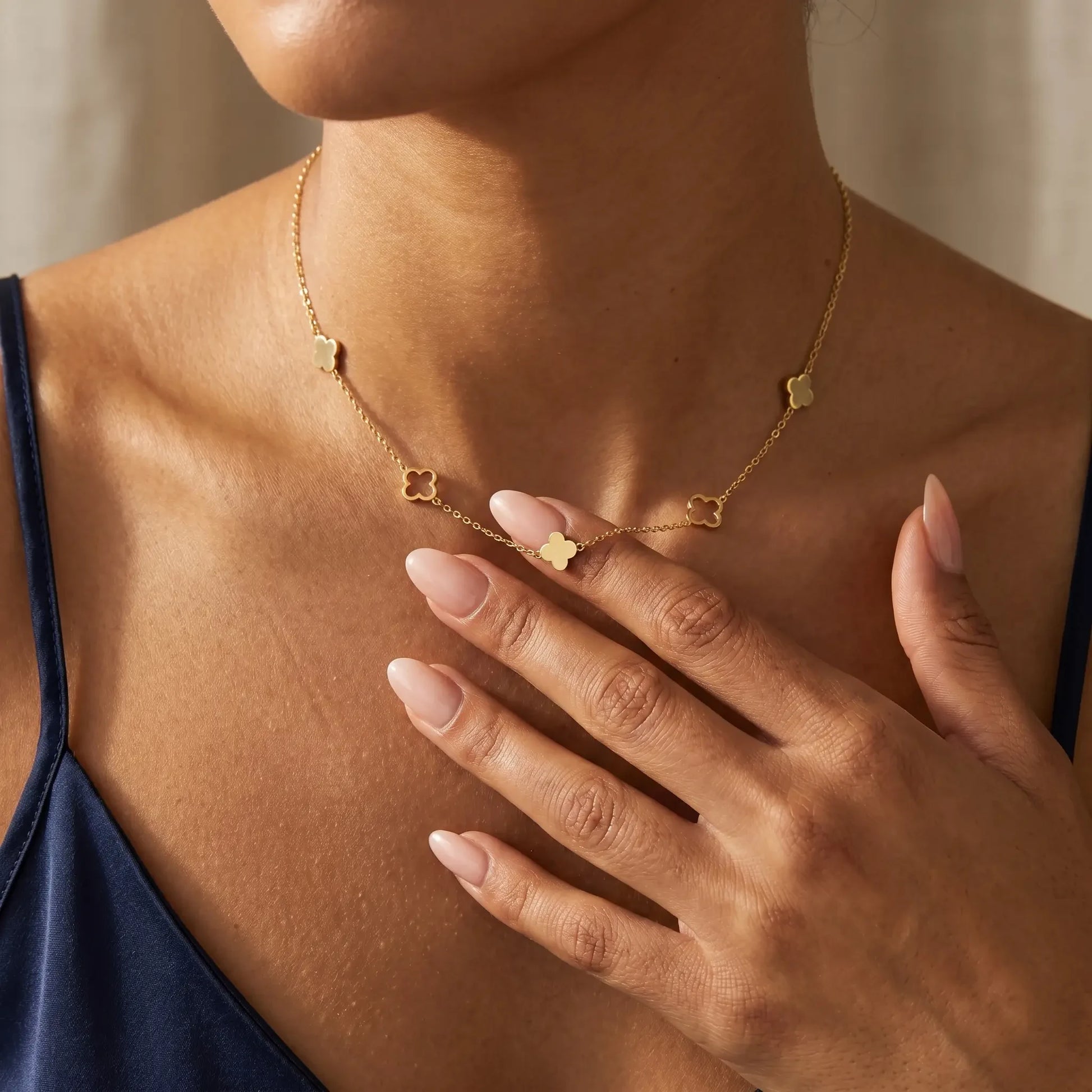 Four leaf clover necklace gold lifestyle fingertips touching pendant