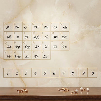 Alphabet chart and number guide displayed on a marble wall with elegant jewelry arranged on a wooden surface.