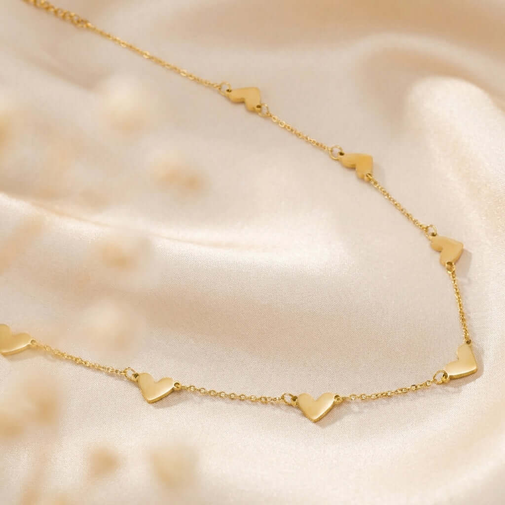 Double Heart Necklace by AUREATE showcased on soft satin fabric.