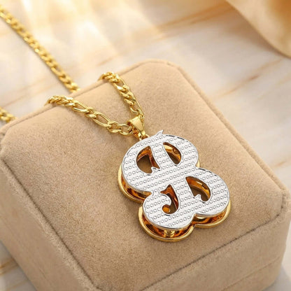 Double Plated Initial Necklace with Figaro Chain by AUREATE displayed on a velvet cushion.