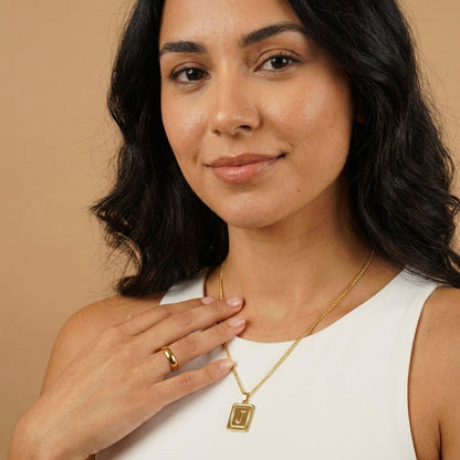 Embossed Initial Necklace with Cuban Chain worn by a model showcasing the gold design from AUREATE.