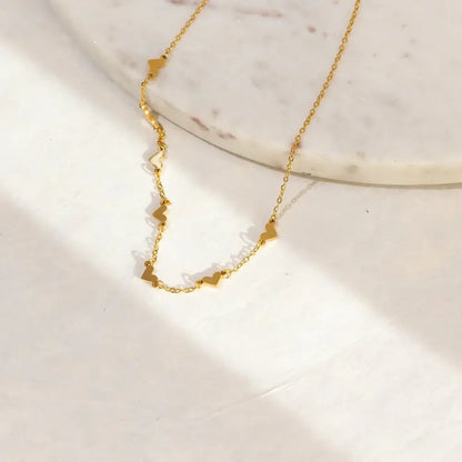 AUREATE Double Heart Necklace showcasing intertwined heart motifs on a marble surface; perfect for layering.