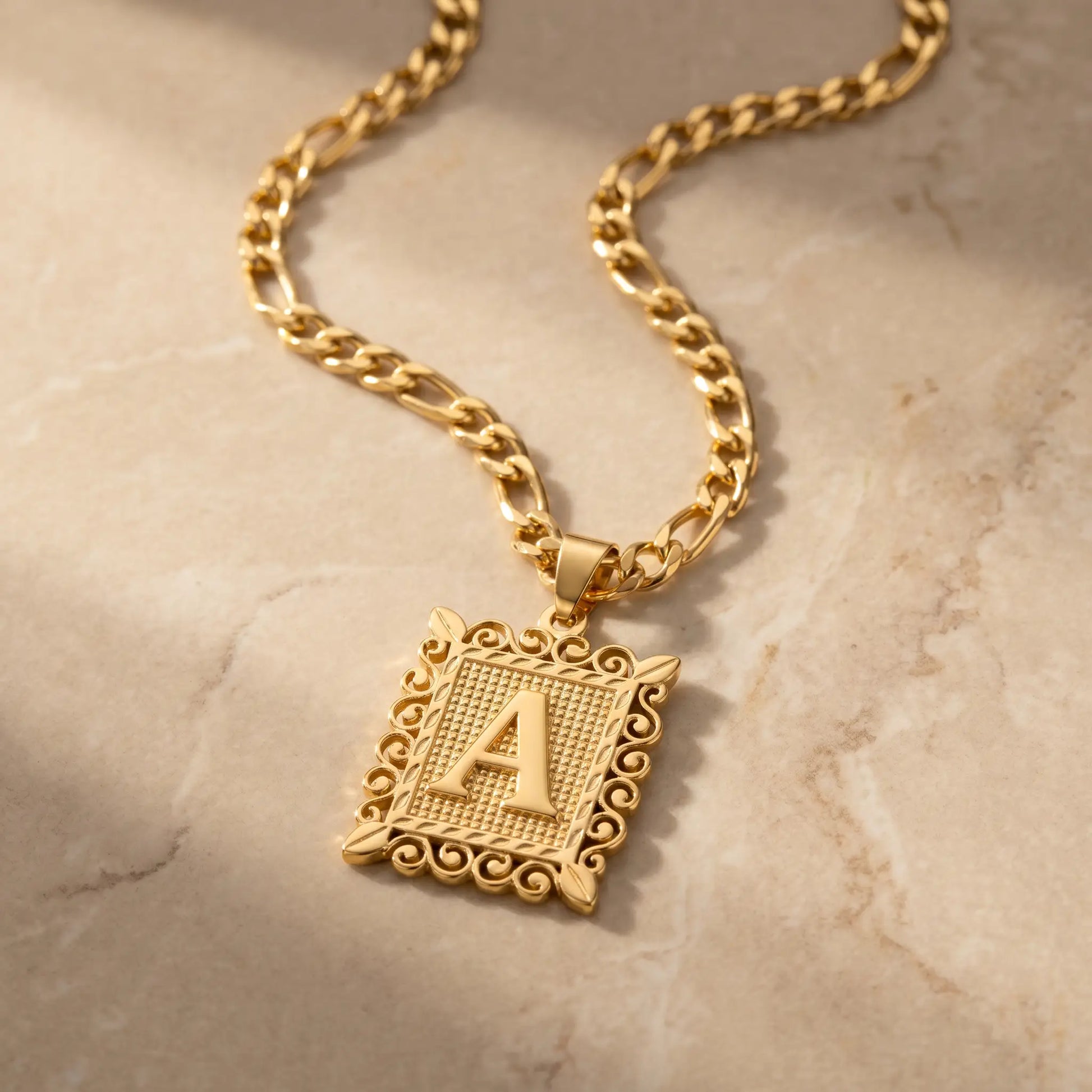 Raised Initial Figaro Pendant 18K gold packshot on travertine