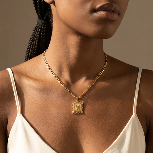 Raised Initial Figaro Pendant 18K gold worn close-up, raised letter on rectangular ornate frame, figaro chain