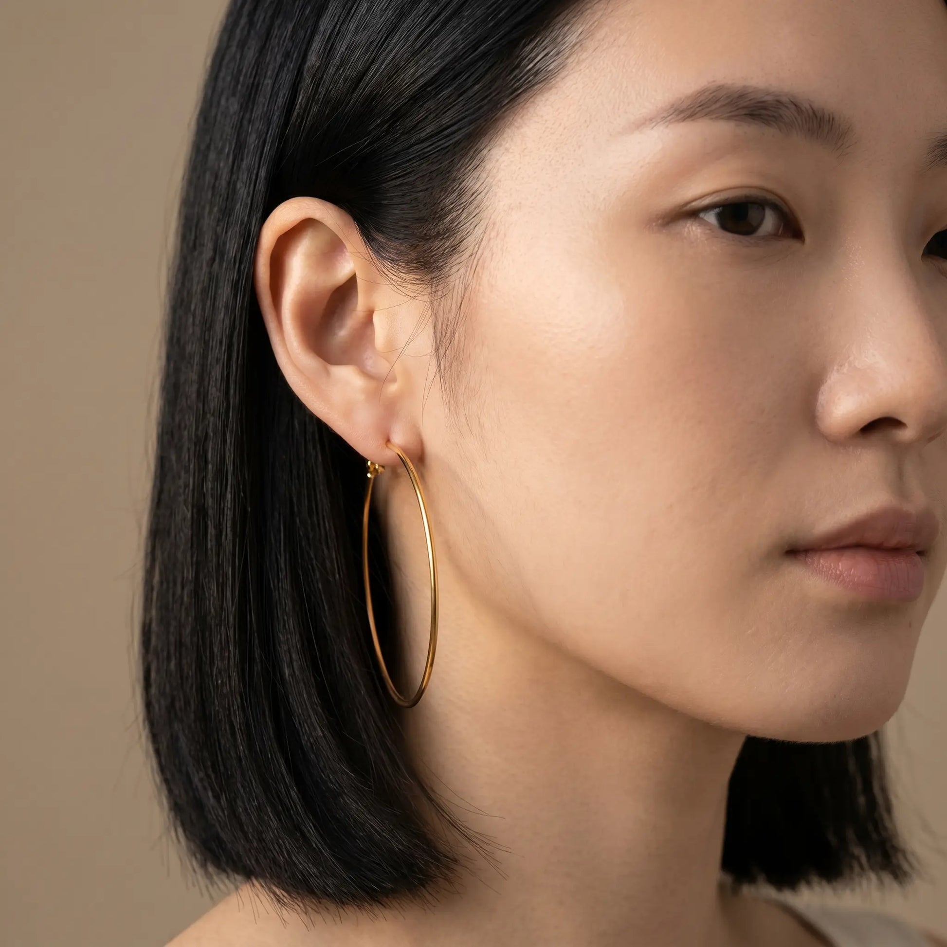 Woman wearing Timeless Gold Hoop Earrings - studio close-up editorial