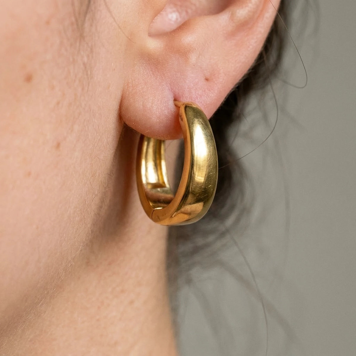 18K gold plated chunky dome hoop earrings, macro detail on the earlobe | SKU: AUR-CHKDOM-G