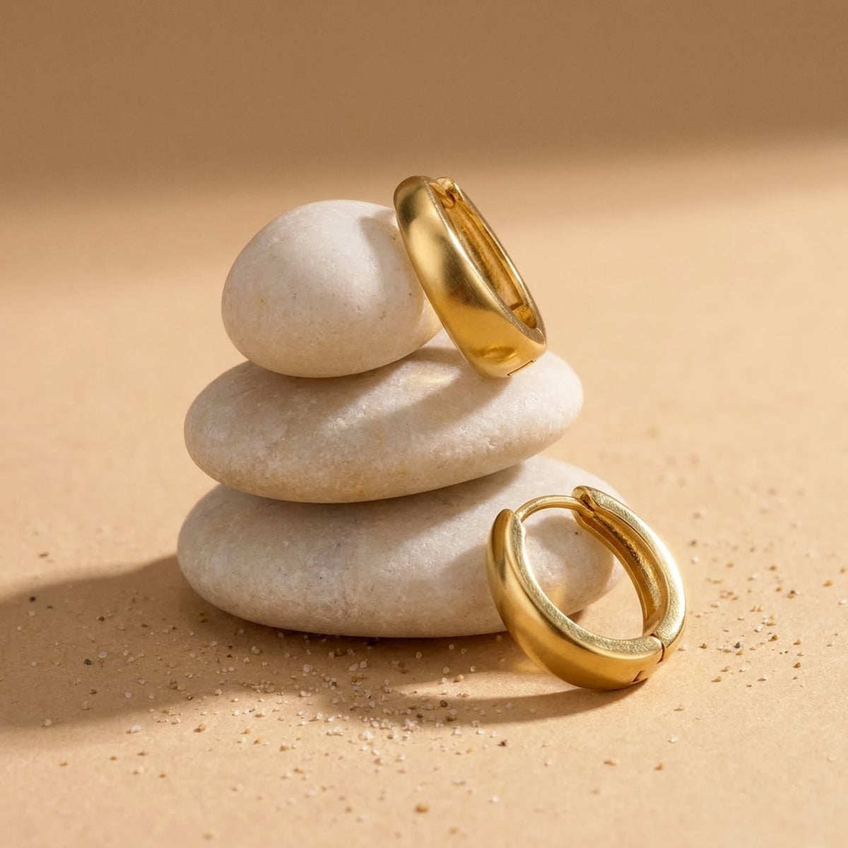 18K gold plated chunky dome hoop earrings, still life on smooth stones | SKU: AUR-CHKDOM-G