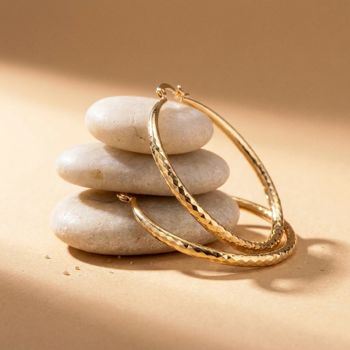 18K gold plated diamond cut large hoop earrings, still life on smooth stones | SKU: AUR-DCTHOP-G