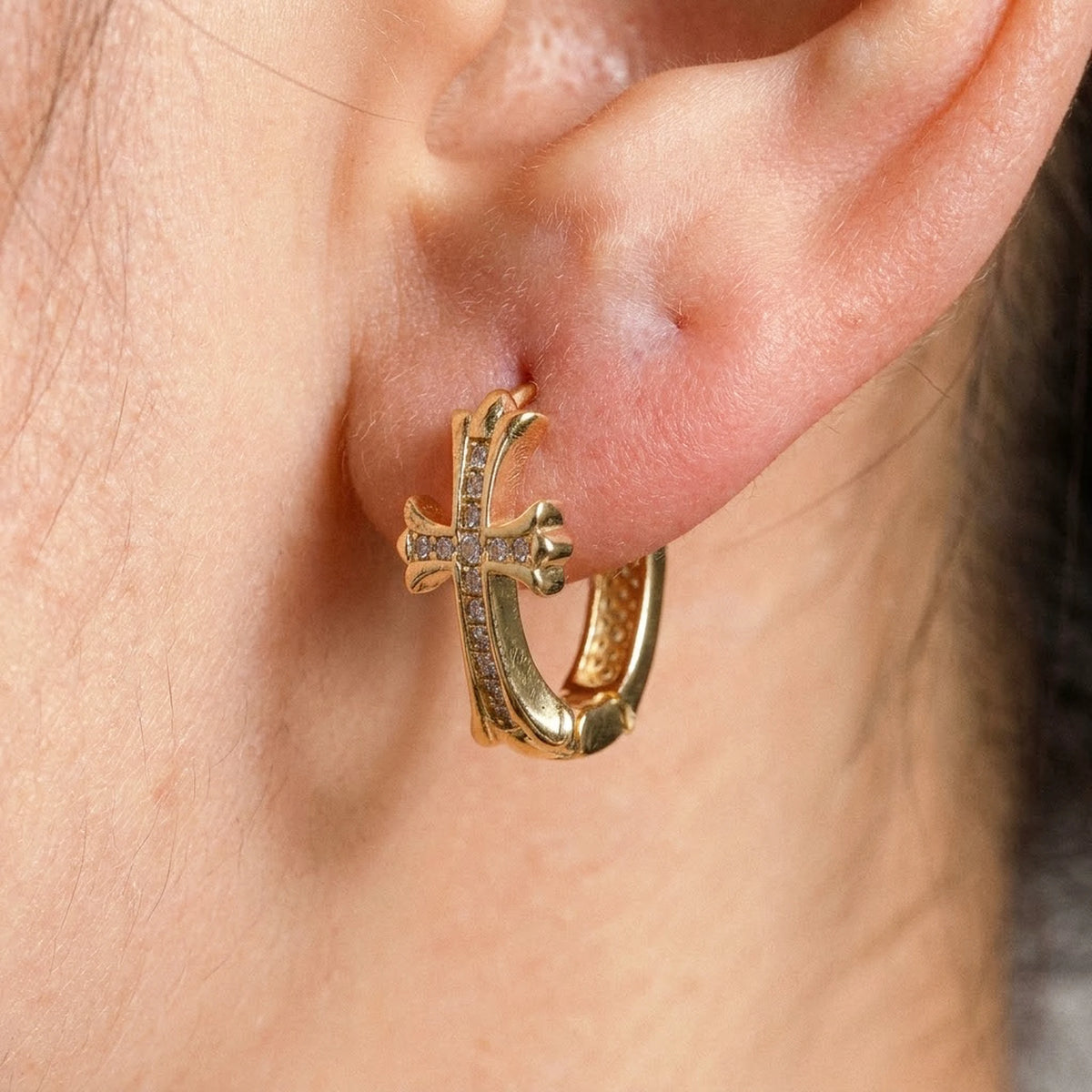 18K gold plated pave cross huggie hoop earrings, macro detail on the earlobe | SKU: AUR-CRXHUG-G