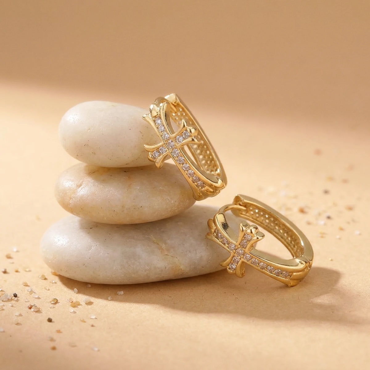 18K gold plated pave cross huggie hoop earrings, still life on smooth stones | SKU: AUR-CRXHUG-G