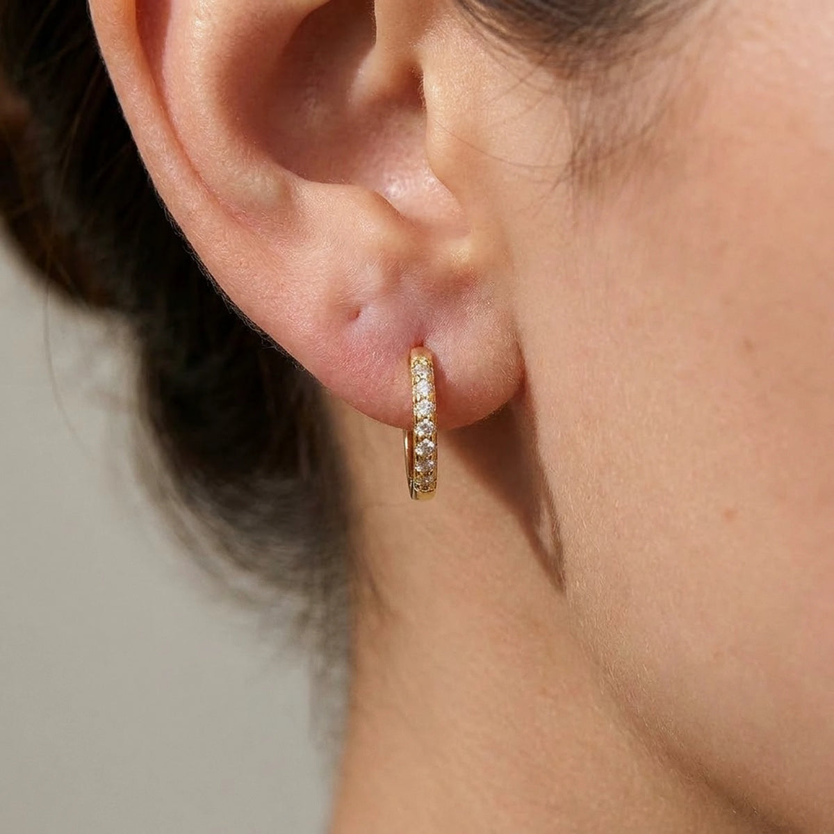 18K gold plated pave huggie hoop earrings, macro detail on the earlobe | SKU: AUR-PVHUGG-G