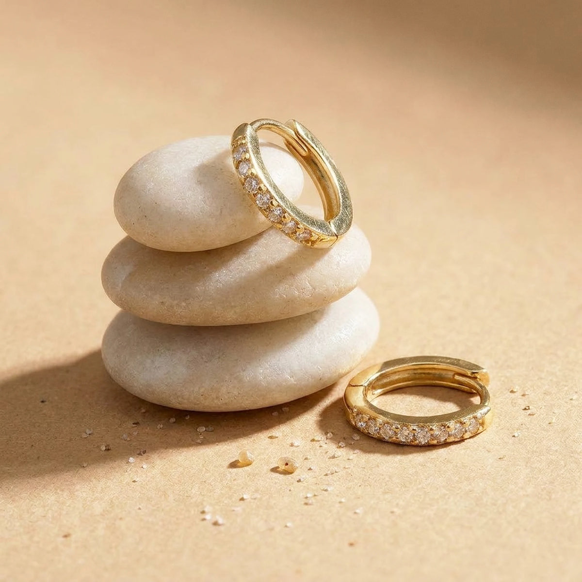 18K gold plated pave huggie hoop earrings, still life on smooth stones | SKU: AUR-PVHUGG-G