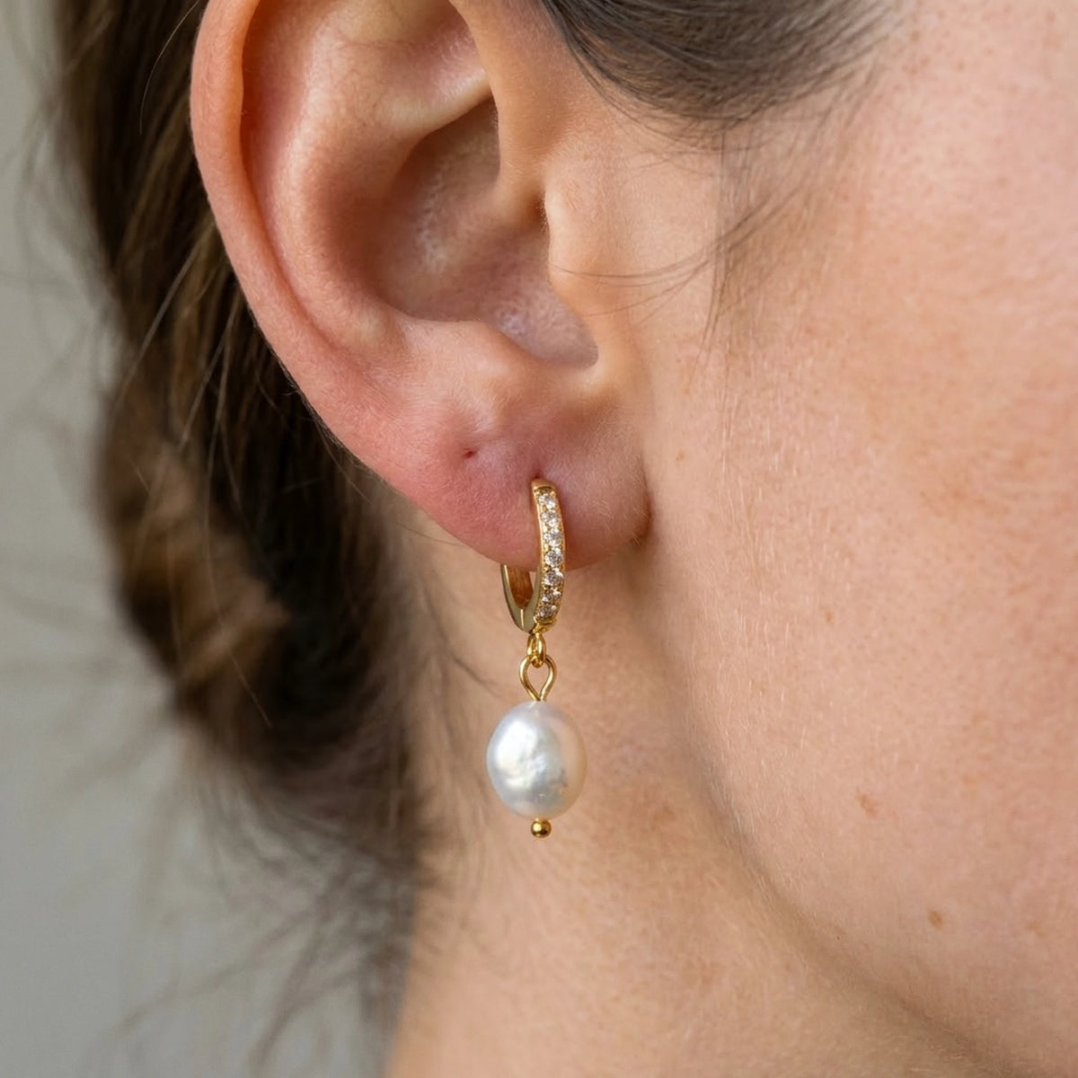 18K gold plated freshwater pearl drop huggie earrings, macro detail on the earlobe | SKU: AUR-PRLHUG-G