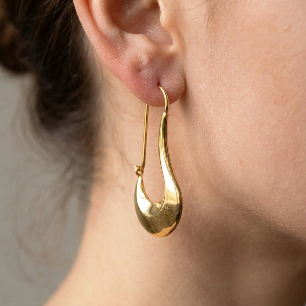 18K gold plated sculpted crescent drop earrings, macro detail on the earlobe | SKU: AUR-SCPCRS-G
