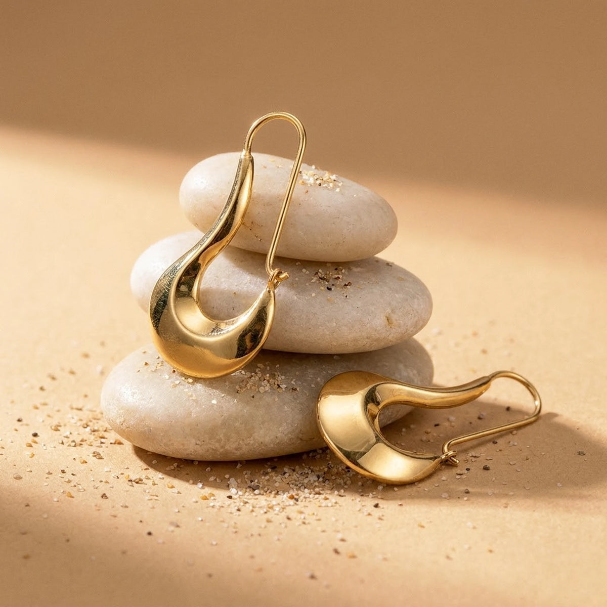 18K gold plated sculpted crescent drop earrings, still life on smooth stones | SKU: AUR-SCPCRS-G