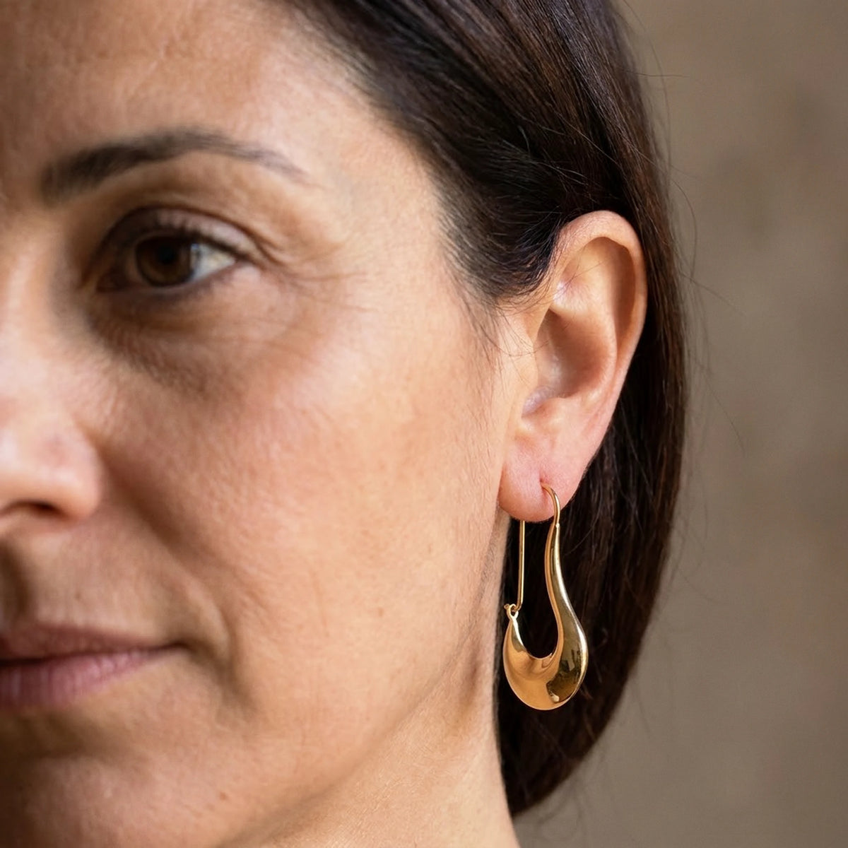 18K gold plated sculpted crescent drop earrings, worn close up on the ear