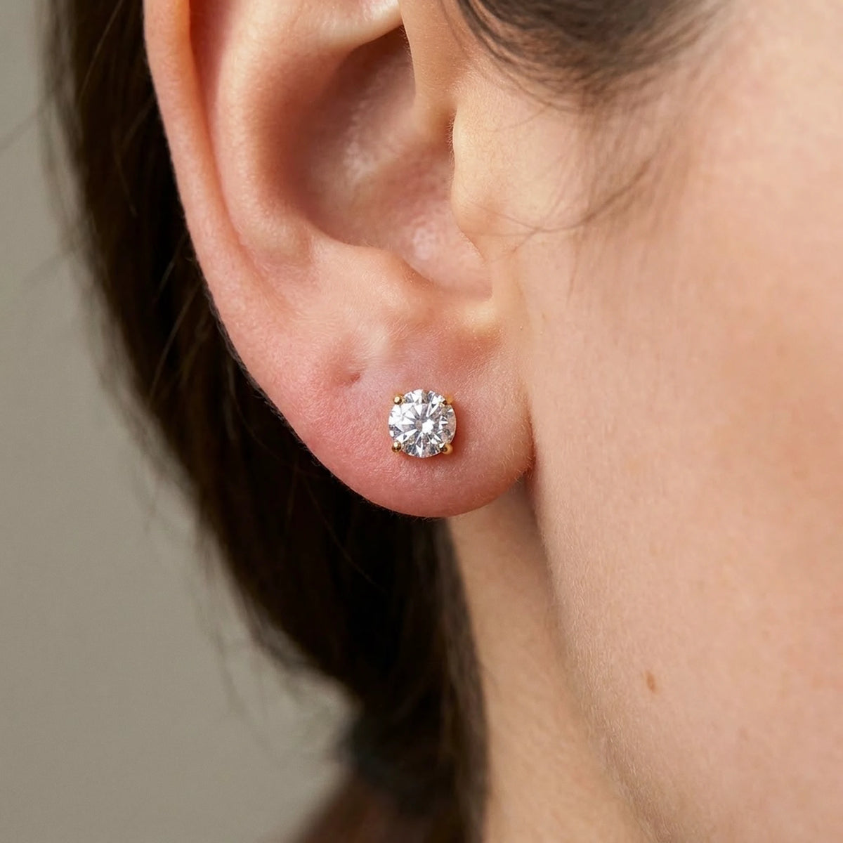 18K gold plated cubic zirconia solitaire stud earrings, macro detail on the earlobe | SKU: AUR-SOLSTD-G