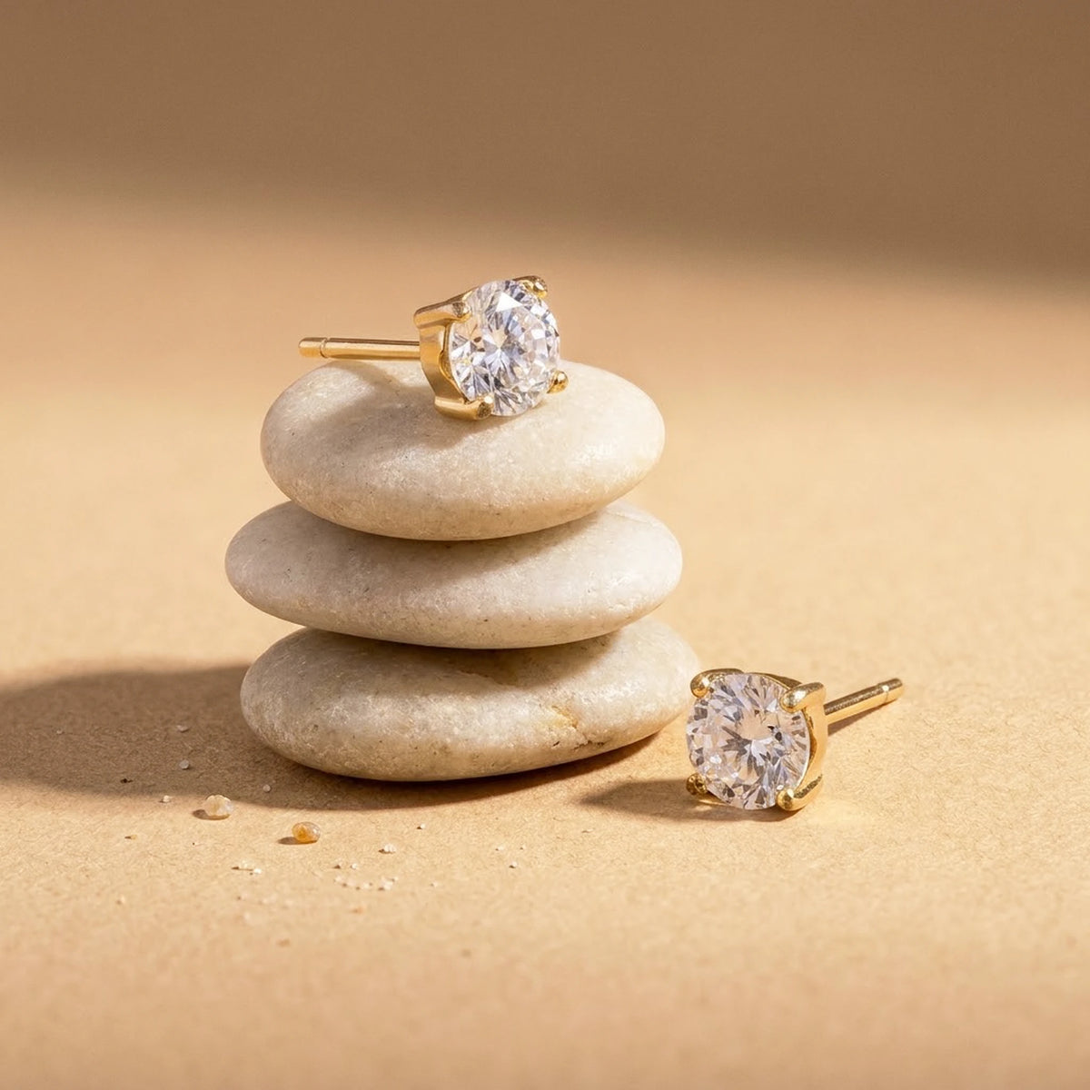 18K gold plated cubic zirconia solitaire stud earrings, still life on smooth stones | SKU: AUR-SOLSTD-G