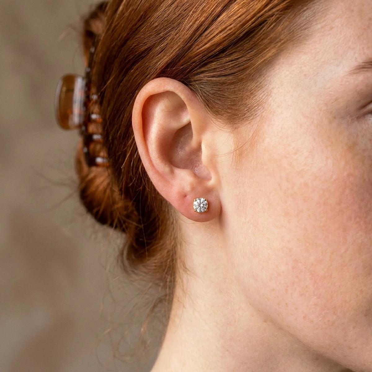 18K gold plated cubic zirconia solitaire stud earrings, worn close up on the ear