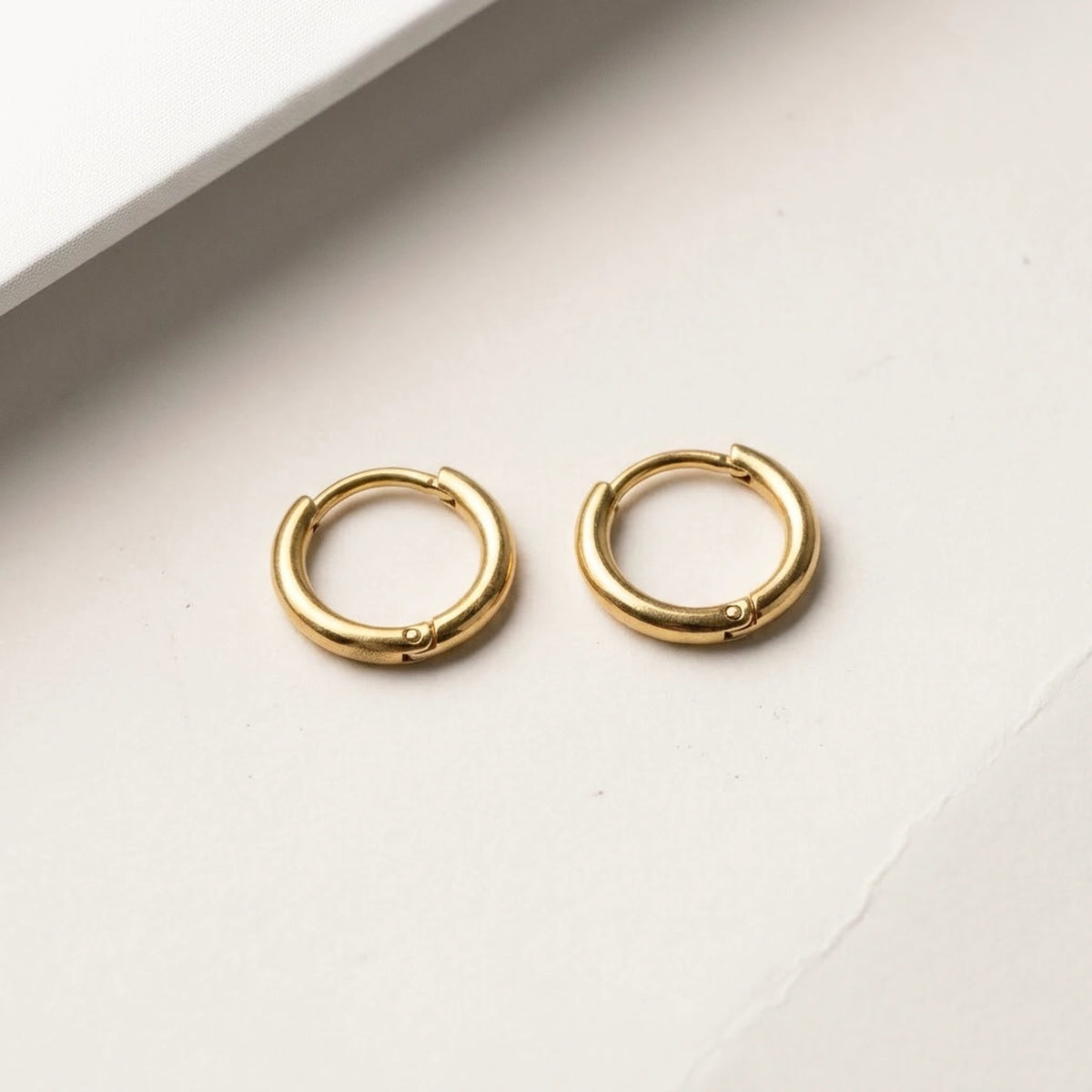 18K gold plated tiny huggie hoop earrings, product shot on white | SKU: AUR-TNYHUG-G