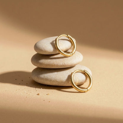 18K gold plated tiny huggie hoop earrings, still life on smooth stones | SKU: AUR-TNYHUG-G