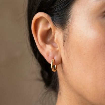18K gold plated tiny huggie hoop earrings, worn close up on the ear