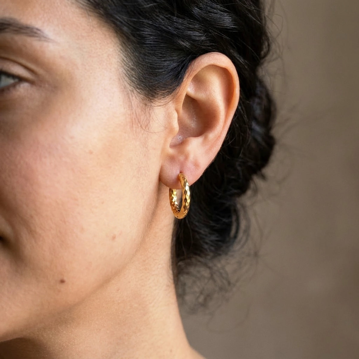 18K gold plated twisted rope huggie hoop earrings, worn close up on the ear