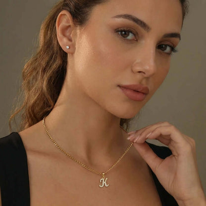 AUREATE Iced Script Letter Necklace worn by a model showcasing the elegant 'K' initial design with crystals.