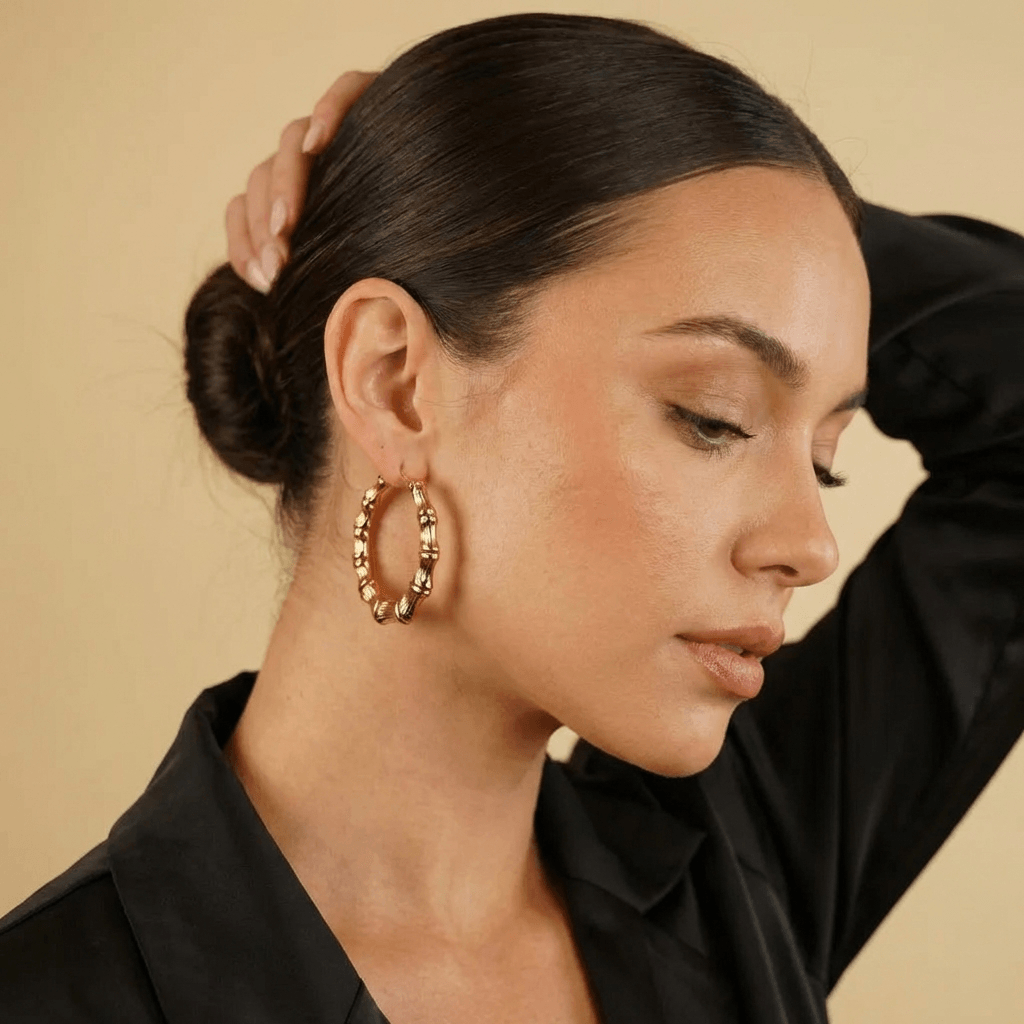 Model showcasing AUREATE Classic Bamboo Hoop Earrings, featuring textured ridges and a rich gold finish.