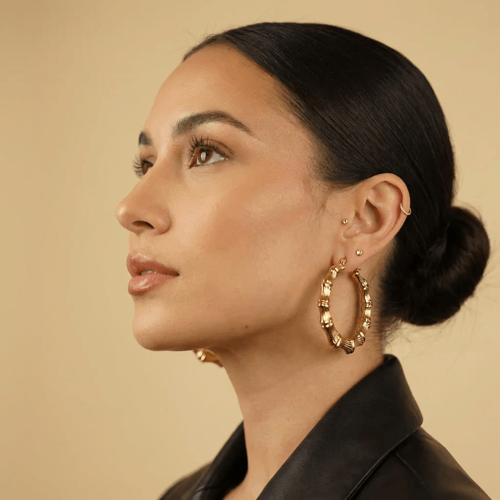 Classic Bamboo Hoop Earrings by AUREATE worn by a model, showcasing the unique textured design and rich gold plating.