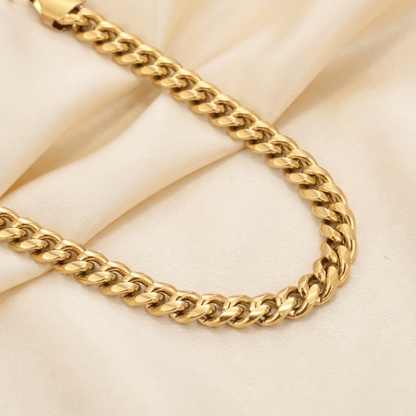 5mm Cuban Link Bracelet by AUREATE, a stylish gold chain on soft fabric background.