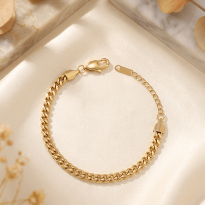 5mm Cuban Link Bracelet by AUREATE on a soft fabric background, showcasing its elegant design and sturdy clasp.