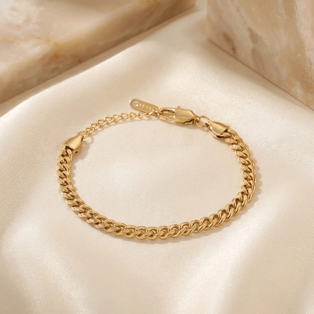 5mm Cuban Link Bracelet by AUREATE, showcasing a stylish gold chain on a satin surface.