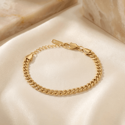 5mm Cuban Link Bracelet by AUREATE, showcasing a stylish gold chain on a satin surface.