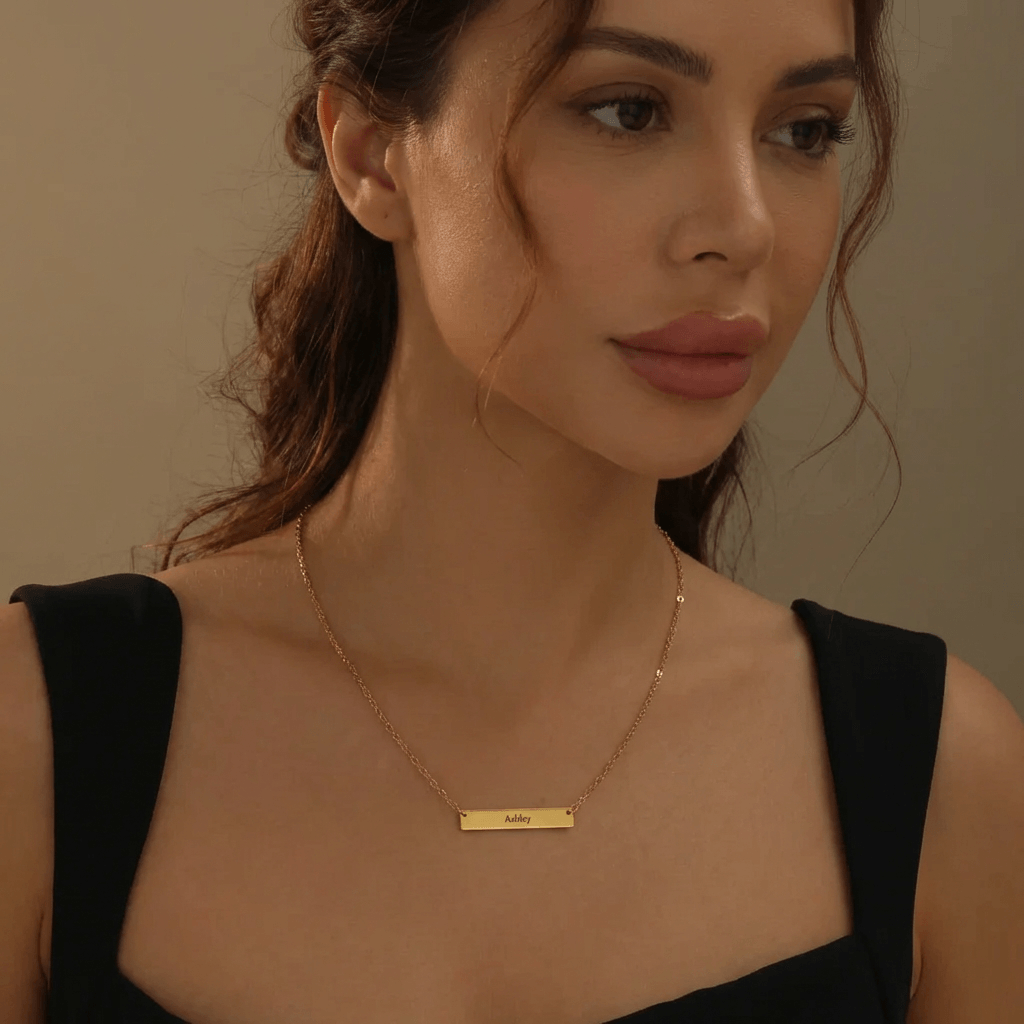 AUREATE Bar Necklace with Engraving worn by a woman, showcasing a gold horizontal bar pendant.